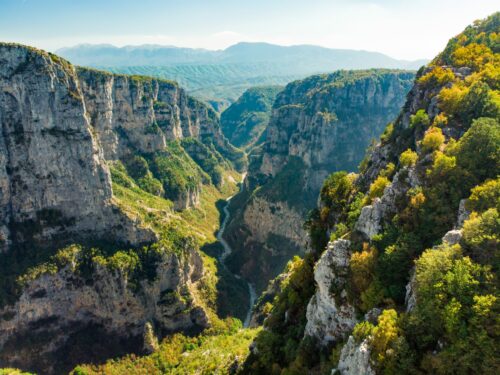 Griechenland Urlaub mit Wandern buchen beim REISEBÜRO Wache in Erfurt; im Bild: grün bewachsene Felsen rechts und links einer Schlucht, auf die man von oben schaut