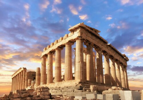 Bucket List Reisen: Athen und Akropolis buchen beim Erfurter REISEBÜRO Wache; im Bild: Die Ruinen der Athener Akropolis vor blauem Himmel und von der untergehenden Sonne beschienen Wölkchen