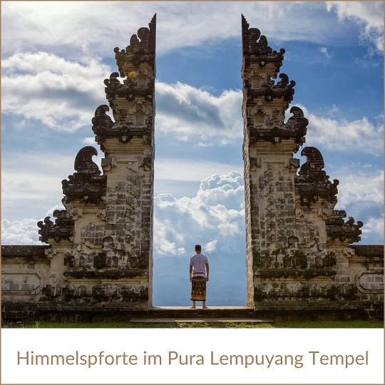 Bali Sehenswürdigkeiten wie die Himmelspforte im Pura Lempuyang Tempel; im Bild ein altes Bauwerk, das aus zwei spitz zulaufenden und verzierten Mauern besteht; in der Mitte dadurch ein nach oben geöffneter Spalt, in dem klein ein Mensch in längerem Rock steht