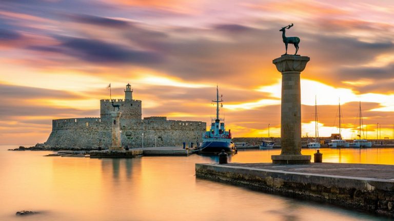 Hafeneinfahrt der griechischen Insel Rhodos mit der Stele eines Hirschs auf der griechischen Insel Rhodos im Sonnenuntergang