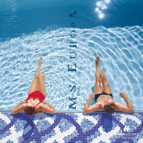 Kreuzfahrt mit Stil Hapag Lloyd Cruises, REISEBÜRO Wache Erfurt; im Bild: Blick von oben auf zwei am Poolrand lehnende, mit den Beinen nach vorne ragende Menschen, auf dem Boden des Pools steht: MS Europa