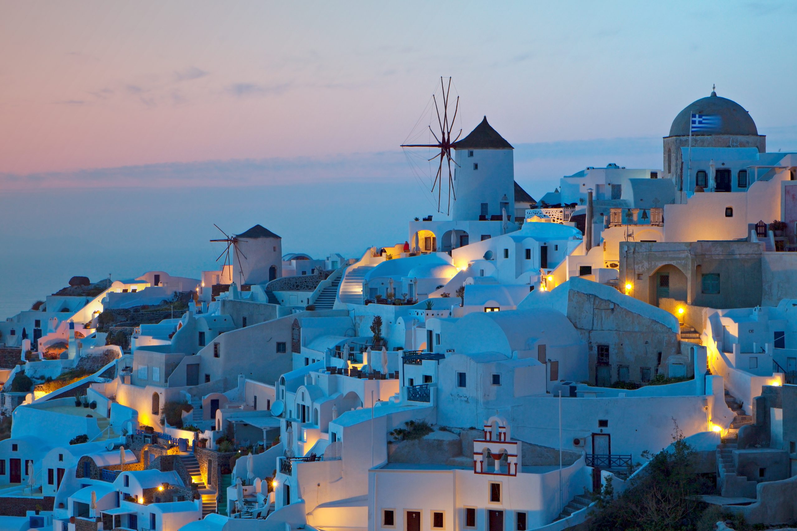 Santorini Urlaub buchen, besonderer Urlaub auf Griechenland beim REISEBÜRO Wache, Erfurt; im Bild: Blick auf die weißen Häuser und eine Windmühle auf Santorin, Griechenland im Sonnenuntergang