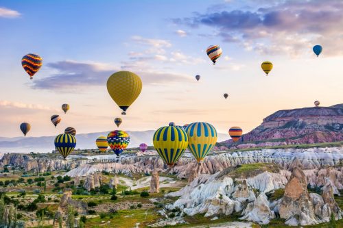 Heißluftballons steigen über hügeliger Landschaft auf: Symbolbild für Erlebnisse buchen, online buchen